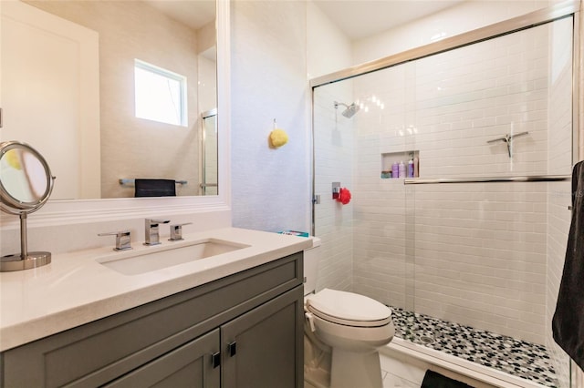 bathroom featuring a shower with door, vanity, and toilet