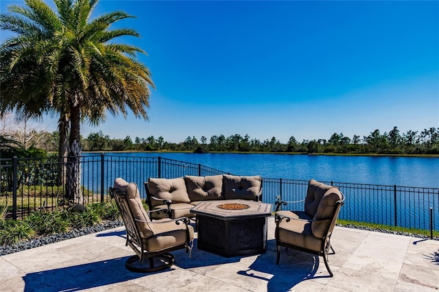 view of patio with a water view and an outdoor living space with a fire pit