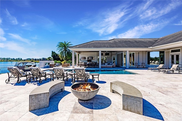 view of pool featuring a fire pit, ceiling fan, a water view, and a patio