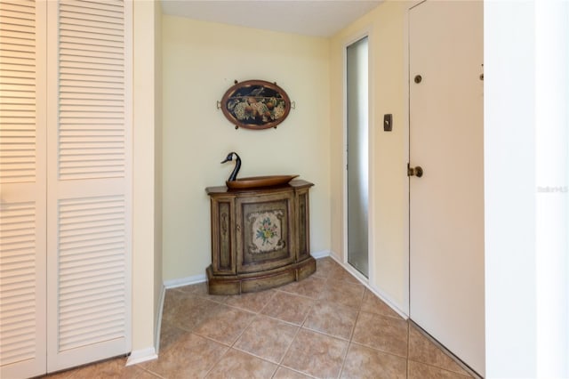 corridor with light tile patterned floors and baseboards