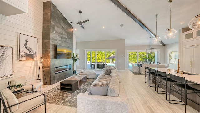 living room with a tile fireplace, wooden walls, ceiling fan, light wood-type flooring, and beam ceiling