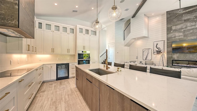 kitchen featuring white cabinetry, a large fireplace, beverage cooler, hanging light fixtures, and black electric cooktop