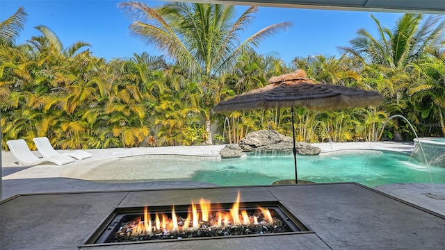 view of swimming pool featuring pool water feature and a fire pit