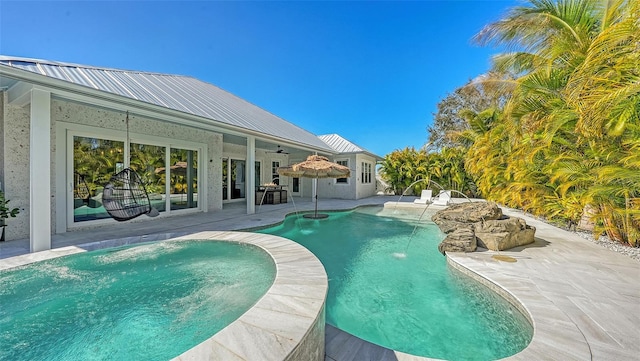 view of swimming pool featuring pool water feature, ceiling fan, a patio area, and an in ground hot tub