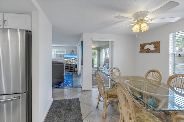 dining space featuring light tile floors, a textured ceiling, and ceiling fan