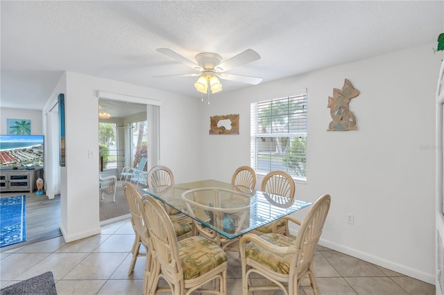 tiled dining area with ceiling fan and a textured ceiling