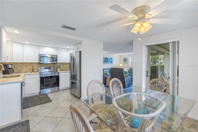 kitchen with tasteful backsplash, stainless steel appliances, ceiling fan, and white cabinetry