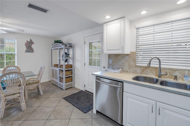 kitchen featuring backsplash, light tile floors, dishwasher, and white cabinetry