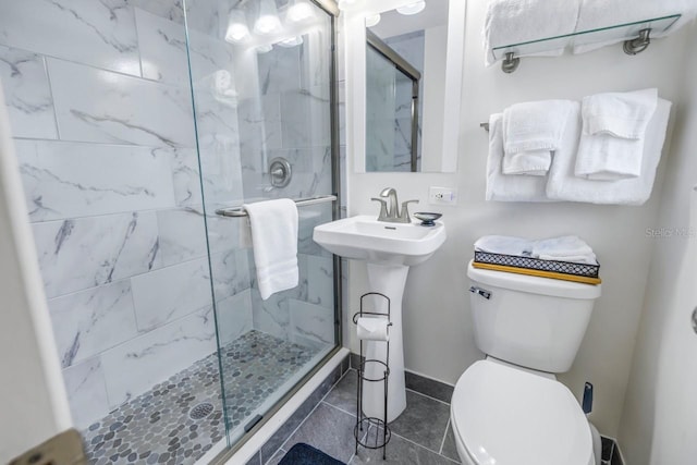 bathroom with an enclosed shower, toilet, sink, and tile flooring