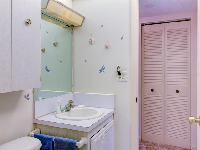 bathroom with vanity, toilet, and a textured ceiling