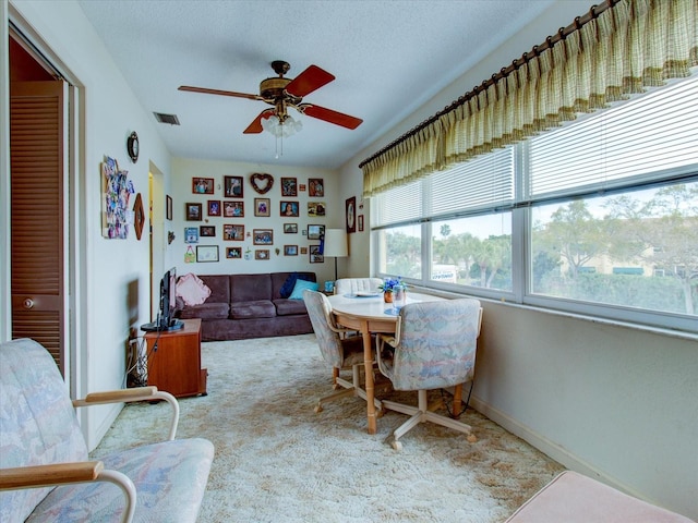 carpeted dining space with a textured ceiling and ceiling fan