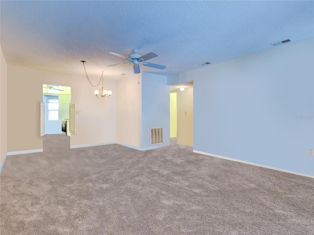 carpeted empty room with a textured ceiling and a notable chandelier