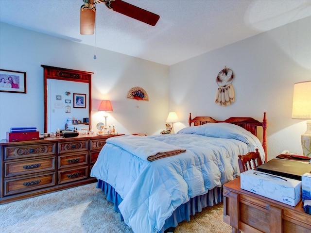 bedroom featuring ceiling fan, light colored carpet, and a textured ceiling