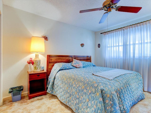 carpeted bedroom featuring ceiling fan and a textured ceiling