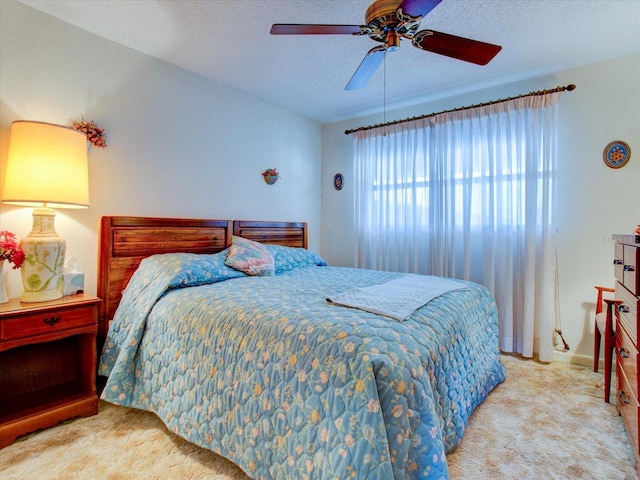 bedroom with a textured ceiling, ceiling fan, and light carpet