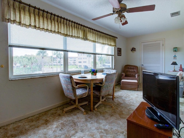 dining area featuring a textured ceiling, ceiling fan, and light carpet