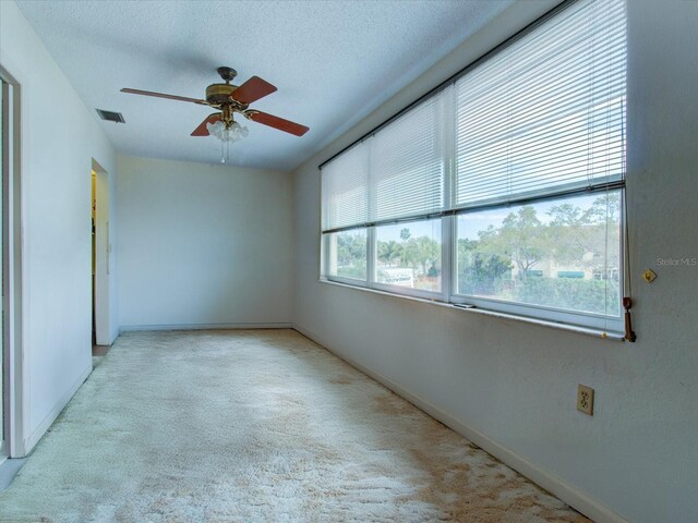 carpeted empty room featuring ceiling fan and a textured ceiling