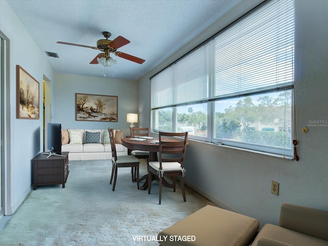 dining area with light carpet, ceiling fan, a healthy amount of sunlight, and a textured ceiling