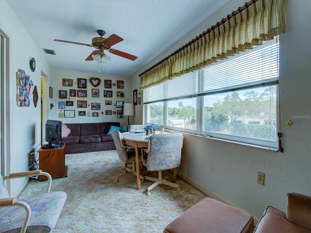 carpeted dining room featuring ceiling fan and a textured ceiling