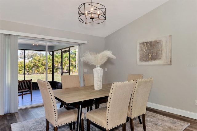 dining space featuring vaulted ceiling, dark hardwood / wood-style floors, and an inviting chandelier