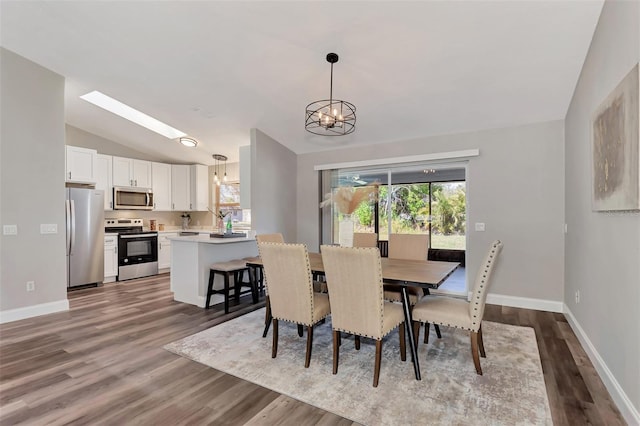 dining room with an inviting chandelier, vaulted ceiling with skylight, and light hardwood / wood-style floors