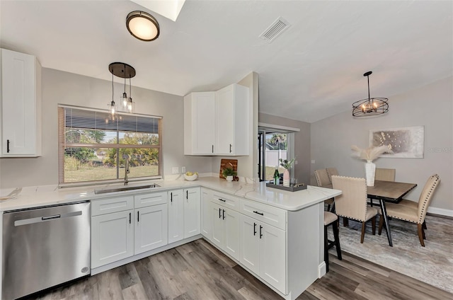 kitchen featuring white cabinets, hanging light fixtures, dishwasher, and light wood-type flooring