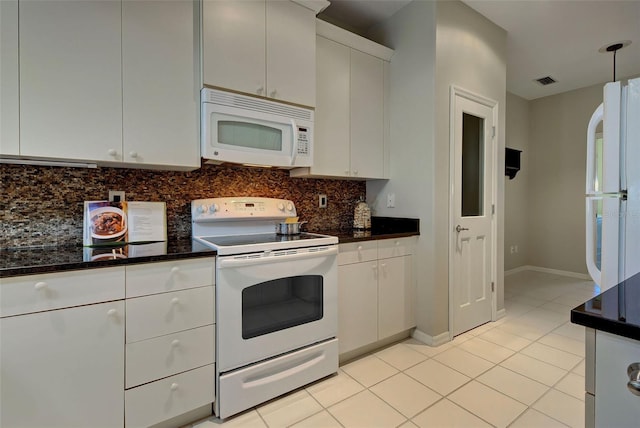 kitchen with white appliances, dark stone counters, white cabinets, light tile flooring, and tasteful backsplash