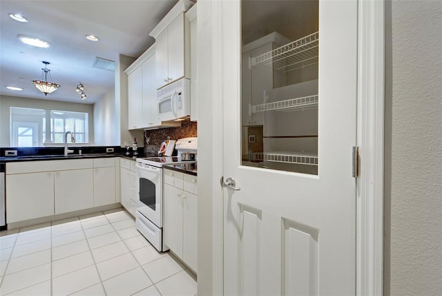 kitchen featuring hanging light fixtures, white appliances, sink, light tile floors, and white cabinets