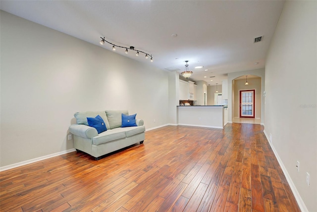 living area with hardwood / wood-style flooring and track lighting