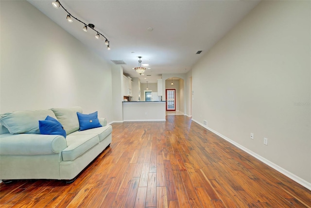 living room featuring rail lighting, a chandelier, and hardwood / wood-style flooring