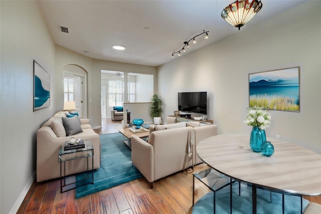 living room with rail lighting, wood-type flooring, and ceiling fan