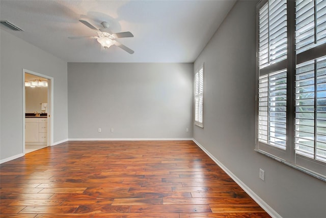 empty room with plenty of natural light, ceiling fan, and dark hardwood / wood-style flooring