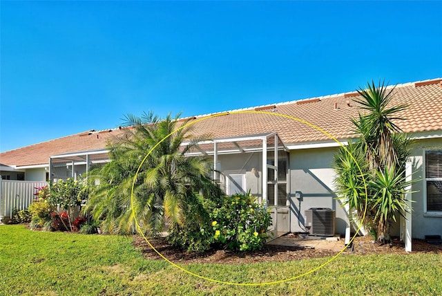 back of property featuring a yard, central air condition unit, and a lanai