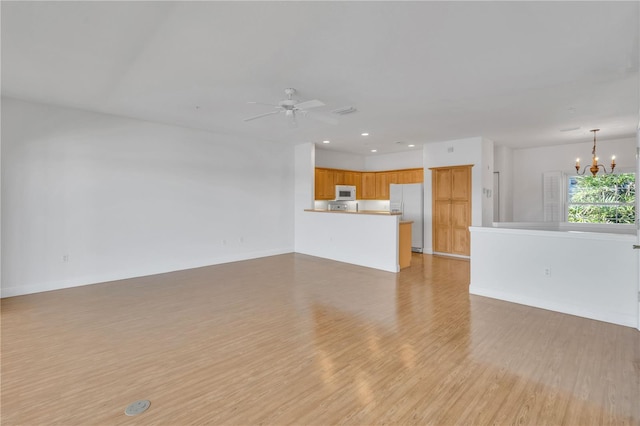 unfurnished living room featuring light hardwood / wood-style flooring and ceiling fan with notable chandelier