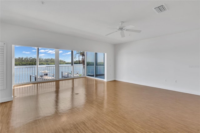 unfurnished room with light hardwood / wood-style flooring, a water view, and ceiling fan