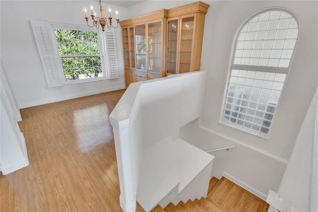 staircase with a chandelier and hardwood / wood-style flooring