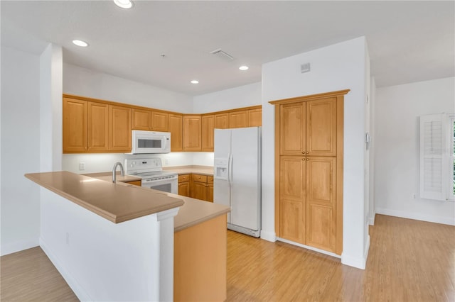 kitchen with white appliances, light hardwood / wood-style flooring, and kitchen peninsula