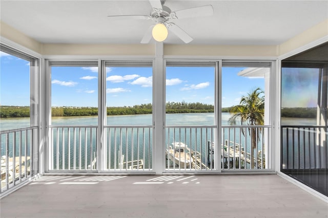 unfurnished sunroom featuring a water view and ceiling fan