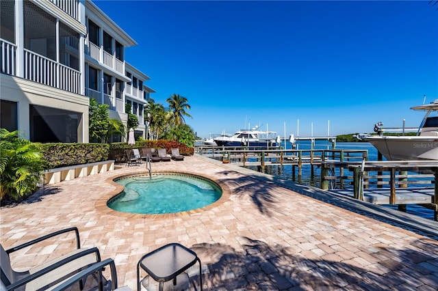 view of swimming pool featuring a patio, a dock, and a water view