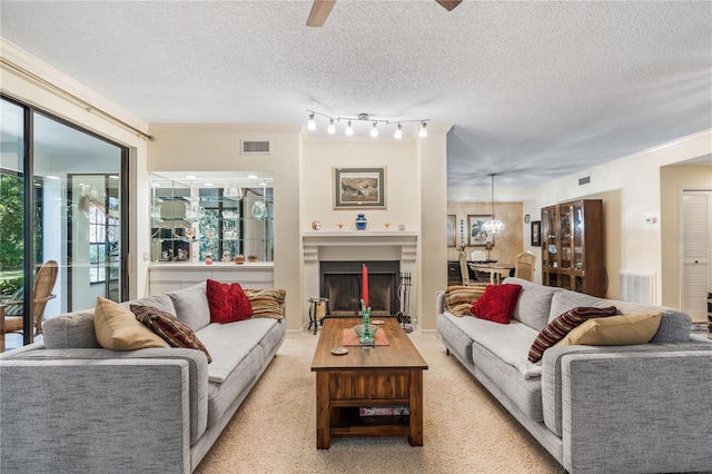 living room featuring light carpet, a textured ceiling, rail lighting, and ceiling fan with notable chandelier