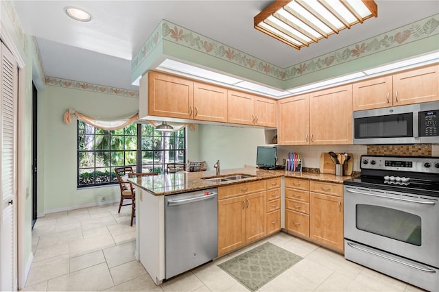 kitchen with kitchen peninsula, appliances with stainless steel finishes, and light stone counters