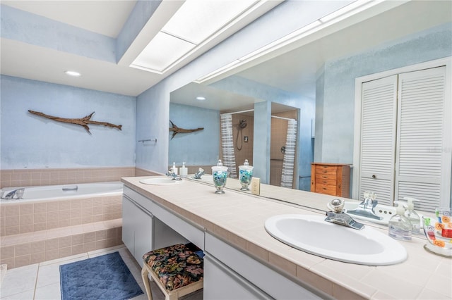 bathroom featuring a relaxing tiled bath, large vanity, tile floors, and double sink