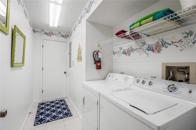 laundry area featuring hookup for a washing machine, a textured ceiling, light tile floors, and washer and clothes dryer