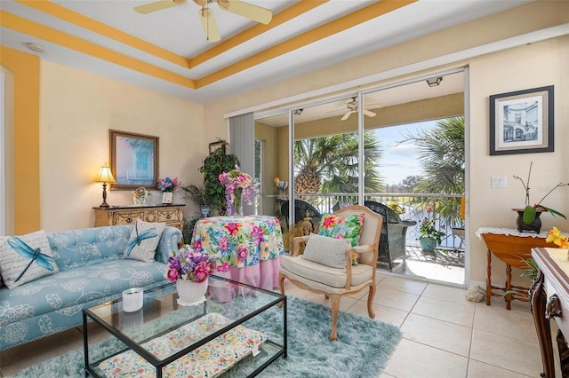 tiled living room with a raised ceiling and ceiling fan