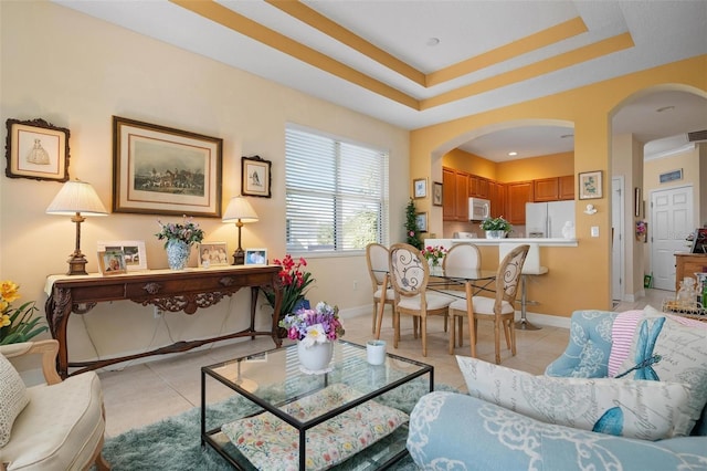 living room featuring a raised ceiling and light tile floors