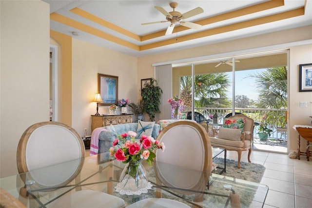 dining room with light tile flooring, a tray ceiling, and ceiling fan