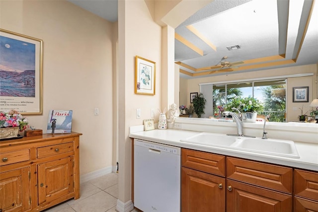 kitchen with a tray ceiling, ceiling fan, light tile flooring, sink, and dishwasher