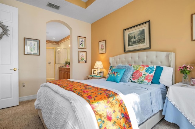 bedroom featuring ensuite bath and light colored carpet