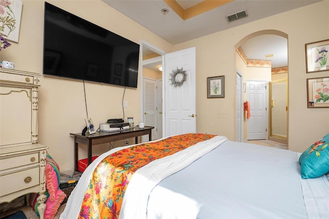 bedroom with ensuite bath and light tile floors