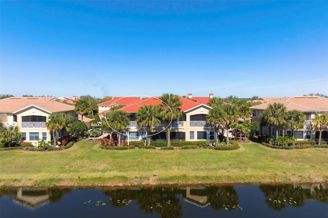 rear view of property featuring a balcony, a water view, and a lawn